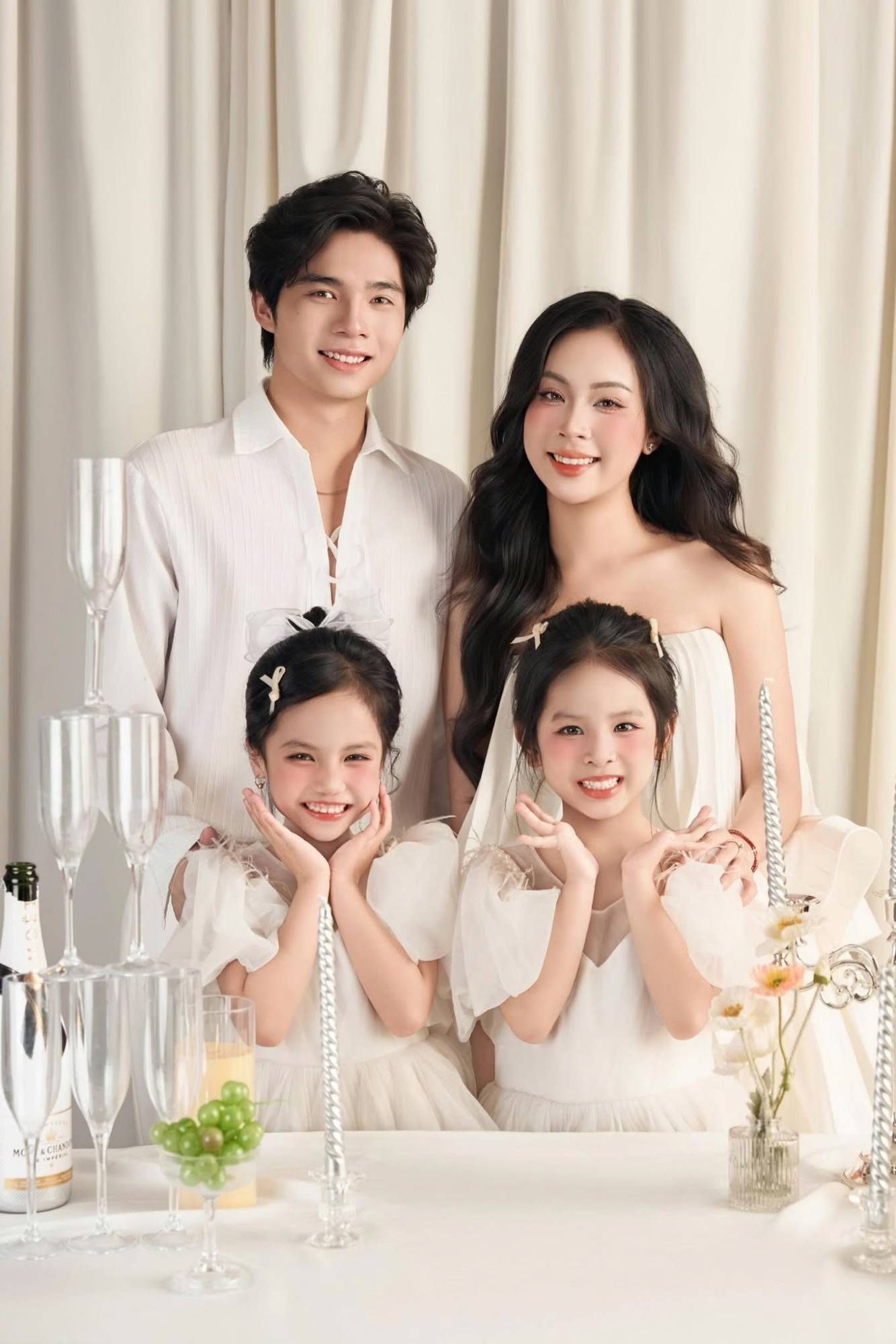 Bố mẹ và hai bé gái bên bàn tiệc trắng